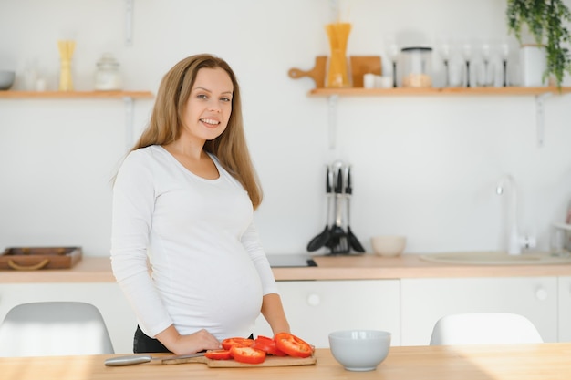 Mulher grávida na cozinha fazendo salada