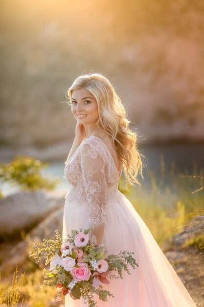 Mulher grávida na natureza. Futura mãe mulher bonita no vestido longo branco ao ar livre