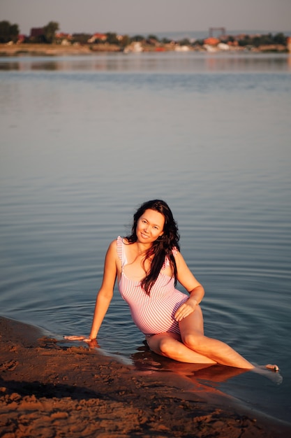 Mulher grávida na praia sorrindo linda mulher grávida em maiô rosa posando na praia ...