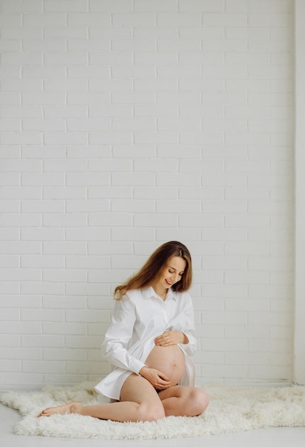 Foto mulher grávida no estúdio em uma camisa branca