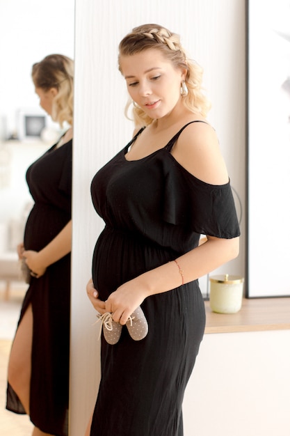 Mulher gravida no vestido preto em casa