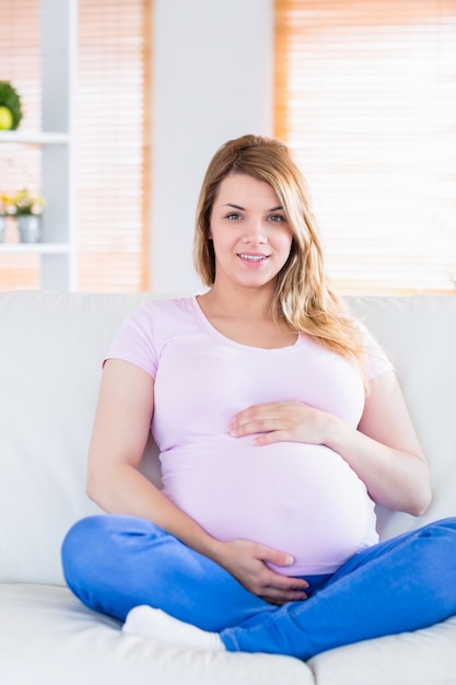 Mulher grávida olhando a câmera com as mãos na barriga