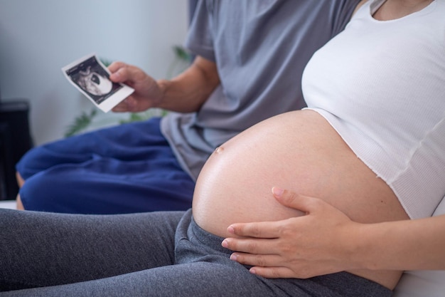 Mulher grávida olhando fotos de ultrassom do feto com o marido Mulheres com 28 semanas de gravidez ou no último trimestre