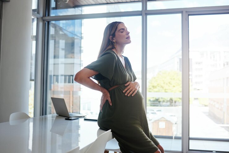 Foto mulher grávida ou dor nas costas no escritório com esgotamento por estresse e relaxar com os olhos fechados na mesa ou mesa pessoa grávida ou com a mão no estômago por ansiedade de risco ou cansada na empresa ou no trabalho profissional