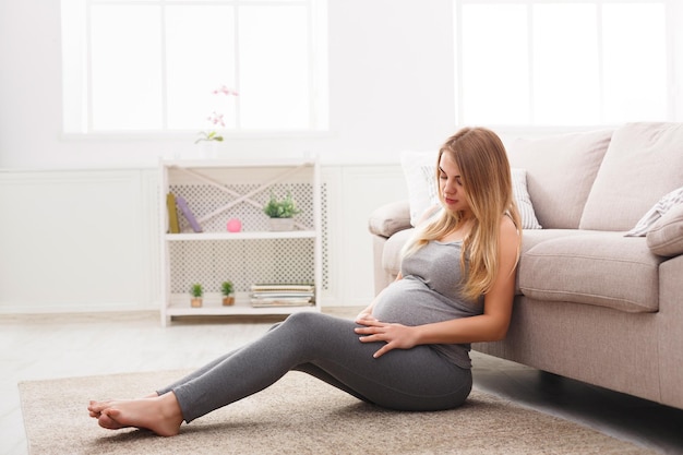 Mulher grávida pensativa, sonhando com uma criança. Jovem feliz expectante pensando em seu bebê e aproveitando sua vida futura. Maternidade, gravidez, conceito de felicidade