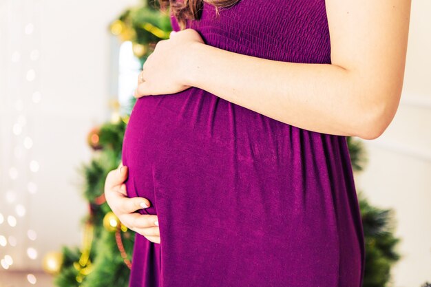 Mulher grávida perto de árvore de natal. barriga closeup