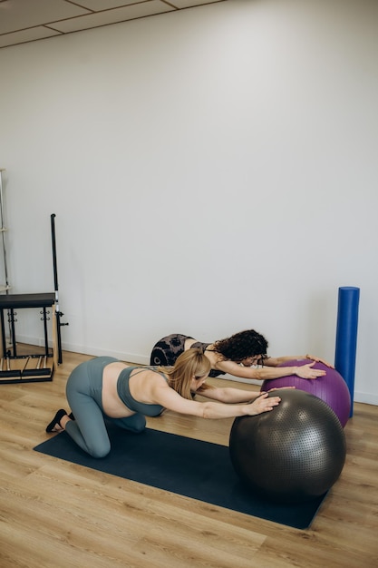 Mulher grávida pilates exercita treino no ginásio com personal trainer