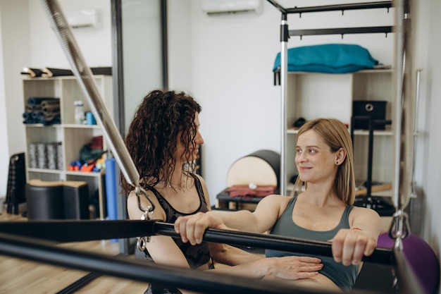 Mulher grávida pilates reformer roll up cadillac exercício com personal trainer