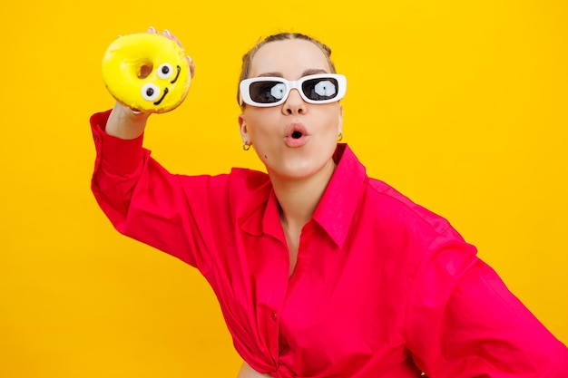 Foto mulher grávida positiva comendo rosquinhas vestindo camisa rosa isolada em fundo amarelo felicidade da gravidez enquanto esperava um filho foto de alta qualidade alimentos prejudiciais durante a gravidez