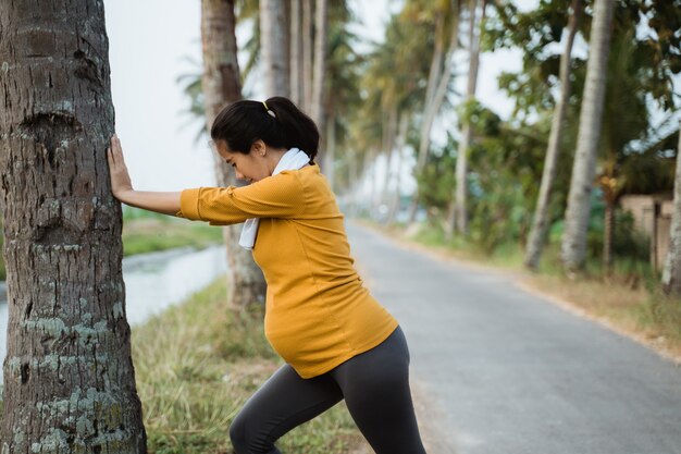 Mulher gravida que exercita ao ar livre