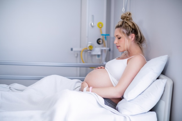 Mulher gravida que relaxa na cama de hospital