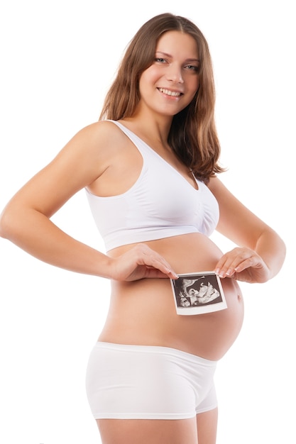 Mulher grávida segurando a barriga e uma foto do ultrassom