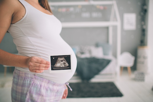 Mulher grávida segurando a ultra-sonografia. Conceito de cuidados de saúde de gravidez