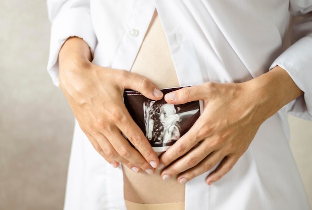 Mulher grávida segurando a ultra-sonografia de seu bebê. Conceito de gravidez e paternidade.