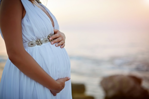 Mulher grávida segurando as mãos na barriga