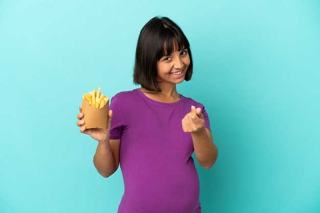 Mulher grávida segurando batatas fritas sobre fundo isolado fazendo gesto de dinheiro