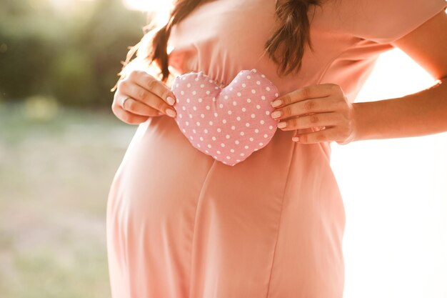 Foto mulher grávida segurando coração rosa ao ar livre maternidade maternidade