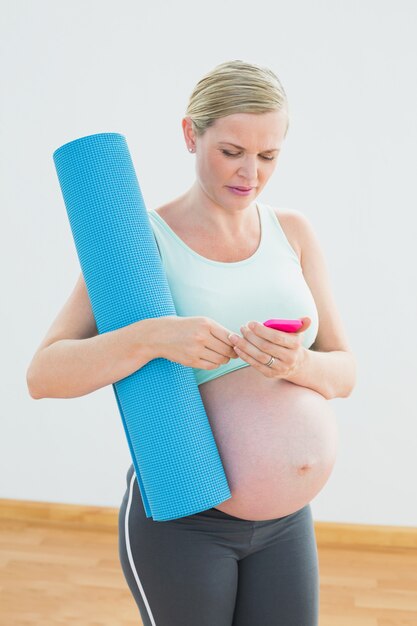 Mulher grávida, segurando, esteira exercício, enviando, um, mensagem texto