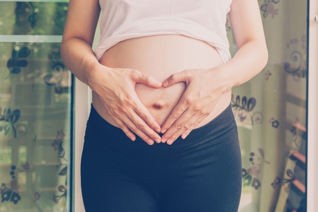 Mulher grávida segurando mão coração forma para bebê em sua barriga