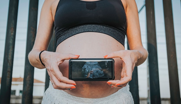 Foto mulher grávida segurando o ultra-som de seu bebê no telefone celular