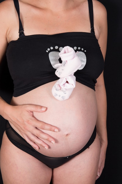 Mulher grávida segurando pequenas meias cor de rosa na frente da barriga