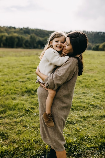 Foto mulher grávida segurando sua filha na barriga mãe e filha passando tempo juntos se divertindo