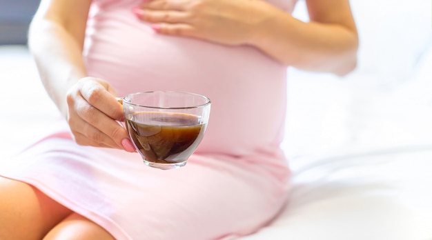 Mulher grávida, segurando uma xícara de café