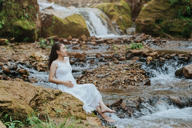 Mulher grávida sentada na cachoeira