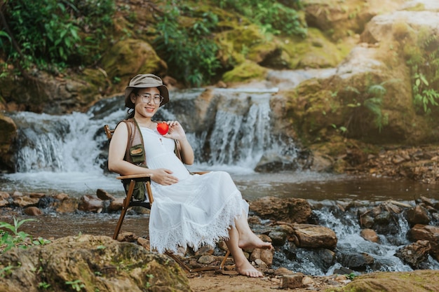 Mulher grávida sentada na cachoeira