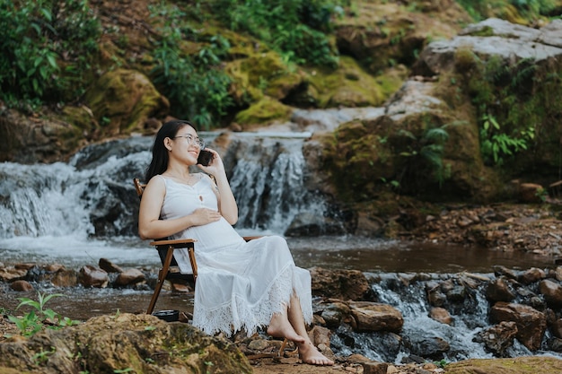 Mulher grávida sentada na cachoeira