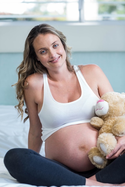 Mulher grávida, sentando, com, um, urso teddy, ligado, dela, cama