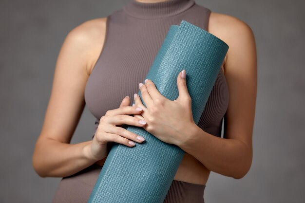 Mulher grávida sorridente em roupas esportivas prontas para ginástica matinal ou exercício Fêmea jovem feliz segue um estilo de vida saudável durante a gravidez segura tapete de ioga para Pilates ou alongamento