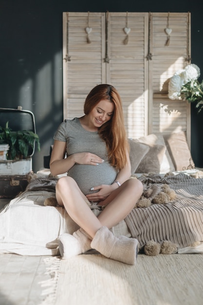 Mulher grávida tocando e olhando para sua barriga