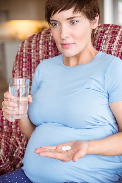 Mulher grávida tomando um comprimido de vitamina