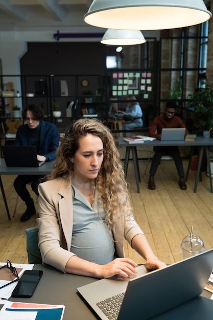 Mulher grávida trabalhando no computador no escritório