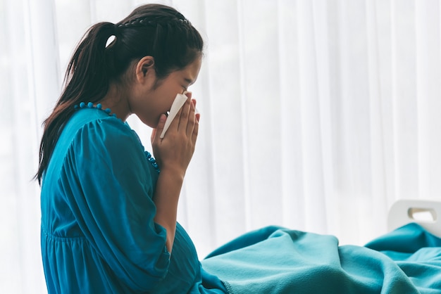 Mulher grávida usando uma toalha de papel para limpar o ranho por causa da gripe.