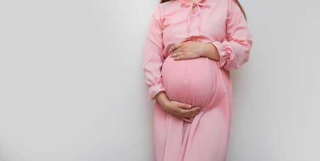 Foto mulher grávida vestida de mãos dadas na barriga