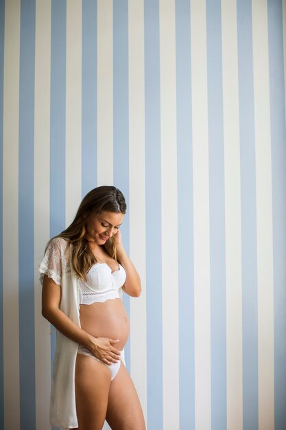 Mulher grávida vestindo lingerie e posando no quarto