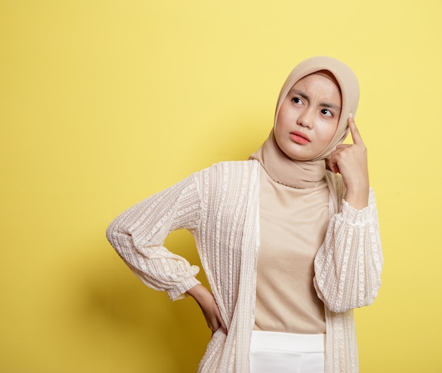 Mulher hijab com uma expressão feliz pensando em algo isolado no fundo amarelo