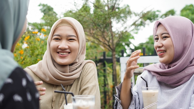 Mulher hijab de grupo asiático sorrindo em um café com um amigo