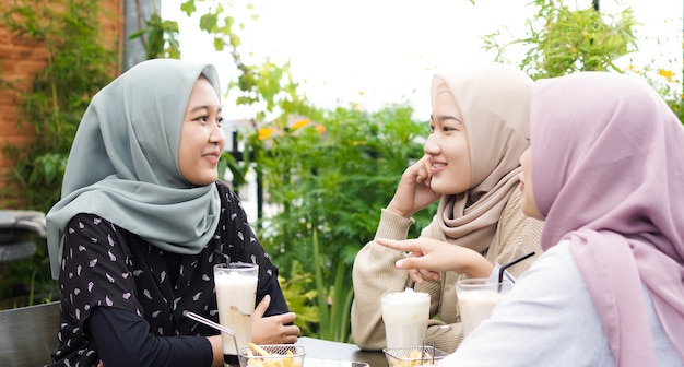 Mulher hijab de grupo asiático sorrindo em um café com um amigo