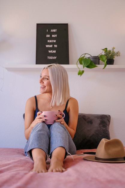 Mulher hipster segurando uma xícara de café isolada no quarto dela