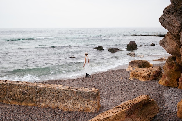 Mulher hipster vestindo vestido perto do mar no outono