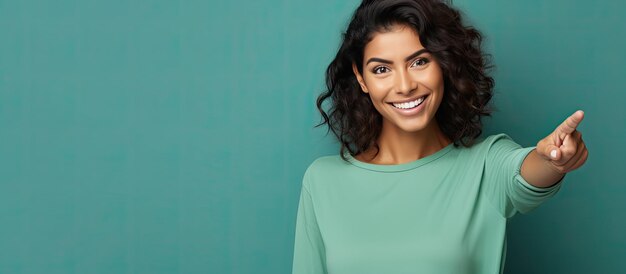 Foto mulher hispânica alegre e sorridente apontando alegremente para o lado e para cima exibindo objeto em área vazia