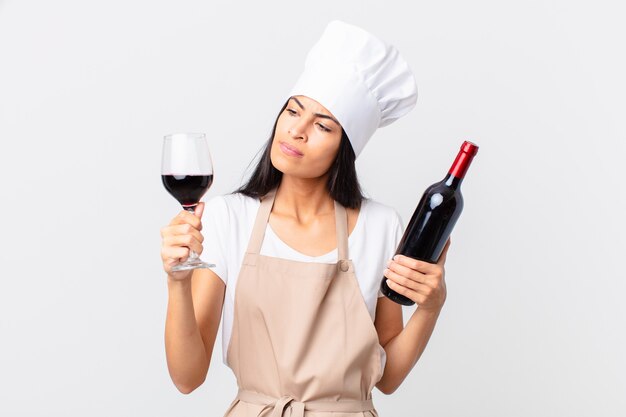 Mulher hispânica bonita chef com uma garrafa de vinho