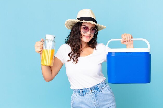 Mulher hispânica bonita com geladeira portátil e suco de laranja