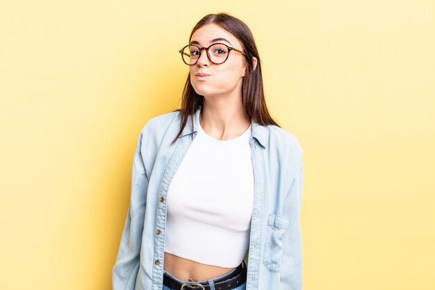 Mulher hispânica bonita com uma expressão boba, maluca e surpresa, bochechas bufantes, sentindo-se recheada, gorda e cheia de comida