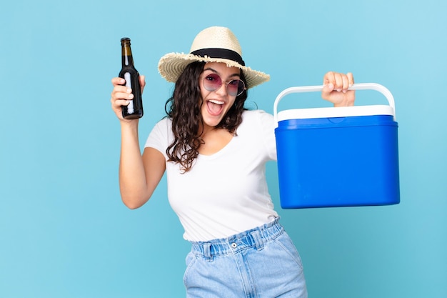 Mulher hispânica bonita com uma geladeira portátil e uma garrafa de cerveja