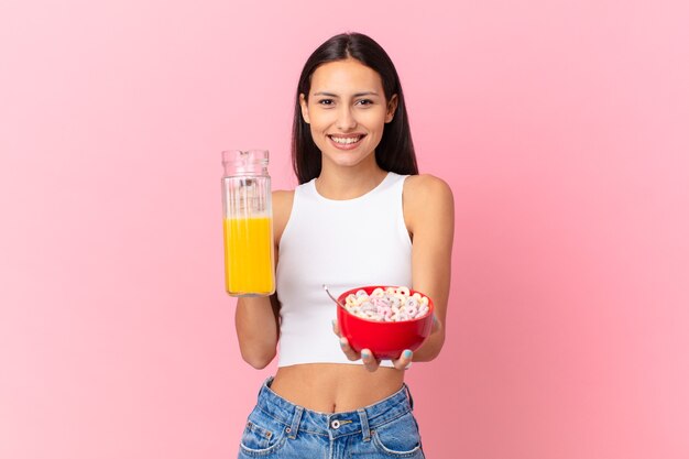 Mulher hispânica bonita com uma tigela de café da manhã com flocos e suco de laranja