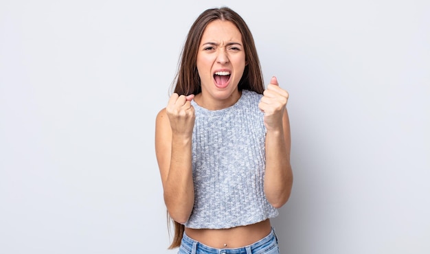 Mulher hispânica bonita gritando agressivamente com olhar irritado, frustrado e irritado e punhos cerrados, sentindo-se furiosa